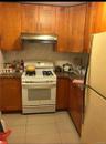 Kitchen featuring white appliances, light tile patterned flooring, brown cabinets, and under cabinet range hood