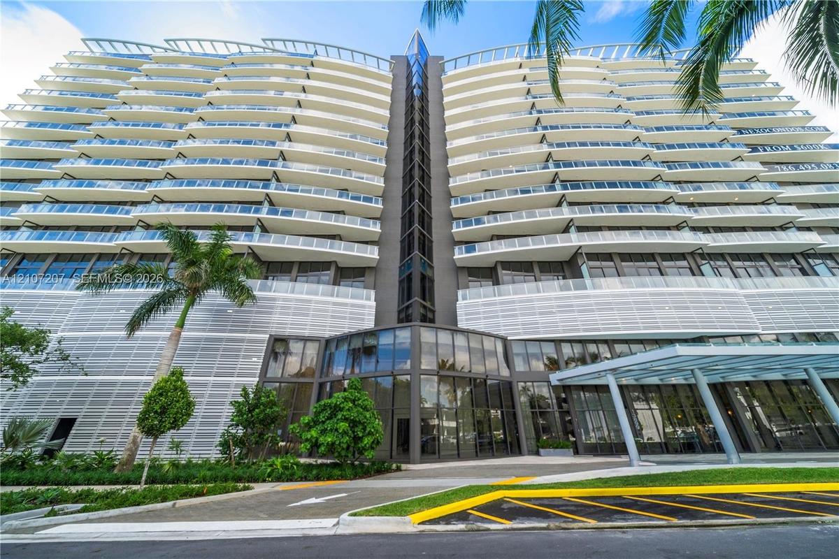 Contemporary high-rise architecture featuring expansive glass balconies, floor-to-ceiling windows, louvered exterior screening, and a prominent glass-