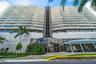 Contemporary high-rise architecture featuring expansive glass balconies, floor-to-ceiling windows, louvered exterior screening, and a prominent glass-