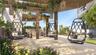 Outdoor terrace featuring a wooden pergola, stone paver flooring, perimeter landscaping, and integrated wall lighting