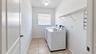 Utility room featuring tiled flooring, a single-pane window, ceiling-mounted light fixture, and built-in wire shelving