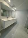 Floating double vanity with a stone countertop, integrated sinks, chrome faucets, and two illuminated mirrors, complemented by large-format tile floor