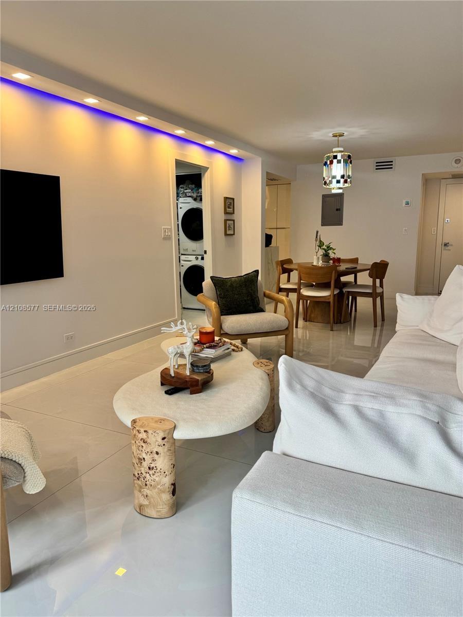 Interior space featuring large-format tile flooring, recessed ceiling lighting with integrated colored accent strips, and a designated laundry area eq