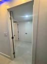 Interior hallway featuring large-format tile flooring, flat-panel doors, matte black hardware, and recessed LED ceiling lighting