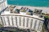 High-rise residential building featuring expansive balcony tiers, direct proximity to the shoreline, and a circular ground-level porte-cochere