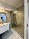 Bathroom featuring a wall-mounted floating vanity, rectangular integrated sink, glass-enclosed shower with large-format tile surround, and an illumina