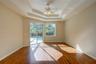 Room featuring tray ceilings, wood-finish flooring, a ceiling fan with integrated lighting, and sliding glass doors with access to a screened-in pool 