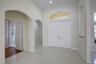 Double front doors with an arched transom window, high ceilings, tile flooring, and decorative arched wall niches