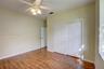 Wood-finish flooring, white paneled closet doors, six-panel interior door, and multi-light ceiling fan