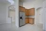 Kitchen featuring wood cabinetry, stone countertops, stainless steel side-by-side refrigerator, tile flooring, and arched architectural detailing