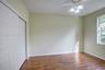 Wood-finish flooring, white sliding closet doors, and a ceiling fan with integrated lighting