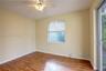 Wood-finish flooring, ceiling fan with integrated lighting, horizontal window blinds, and sliding glass door
