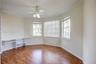 Room featuring wood-finish flooring, built-in shelving, a ceiling fan with integrated lighting, and multiple windows with horizontal blinds