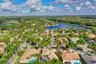 Aerial perspective featuring residential lots with private swimming pools, tile roofing, and mature tropical landscaping within a waterfront community
