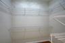 Walk-in storage space featuring multi-tiered white wire shelving and wood-finish flooring