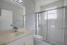 Bathroom featuring a vanity with integrated sink, large wall-mounted mirror, walk-in shower with a glass enclosure, rainfall shower panel system, and 