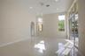 High-ceiling living area featuring large-format tile flooring, a multi-tier contemporary pendant light fixture, arched entryways, and sliding glass do