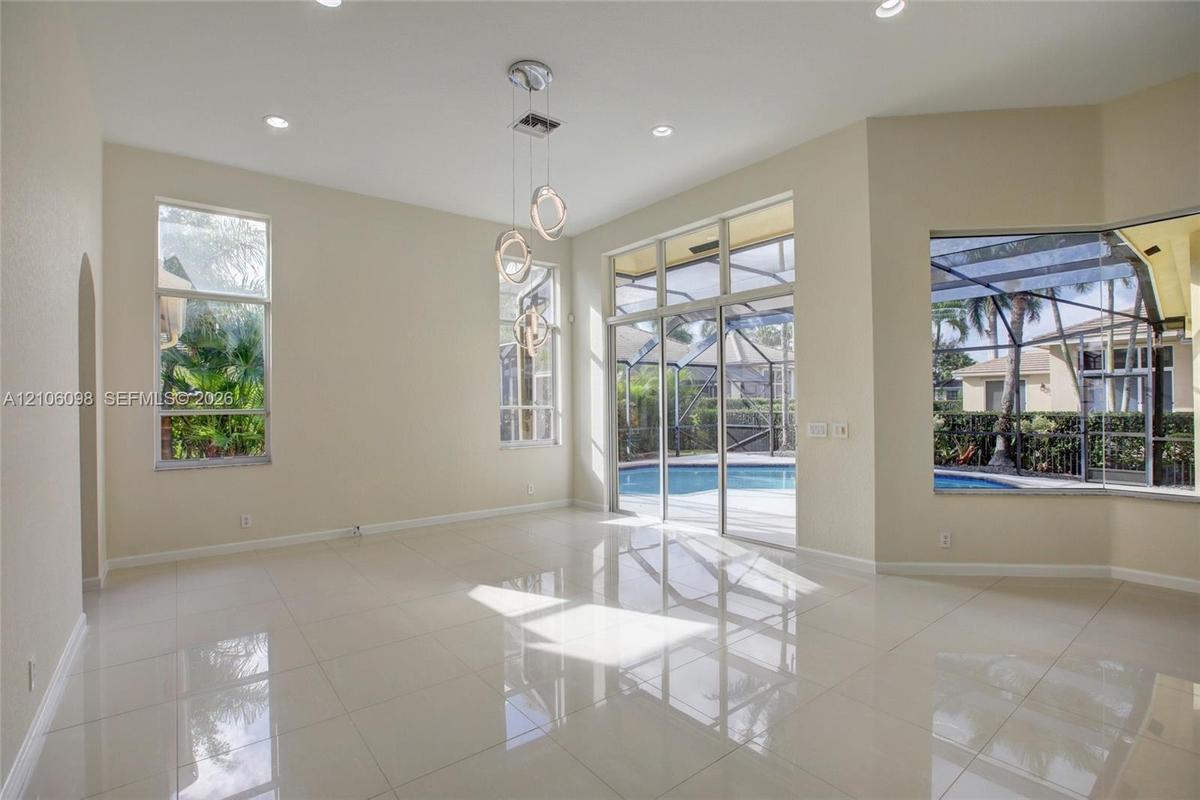 High ceilings with recessed lighting, large-format tile flooring, multi-light pendant fixture, floor-to-ceiling windows, and sliding glass doors openi