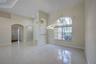 Open-concept interior featuring polished tile flooring, arched wall cutouts, a contemporary circular pendant light fixture, and a large arched multi-p
