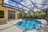 Screened-in patio featuring a concrete pool deck, geometric swimming pool with tiled coping, and large sliding glass doors