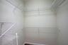 Walk-in storage area featuring multi-level white wire shelving and neutral wall finishes