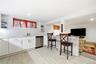 Kitchen featuring white cabinetry, subway tile backsplash, stainless steel dishwasher, tile flooring, and a peninsula with a countertop