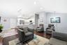 Open-concept interior featuring vaulted ceilings, recessed lighting, white cabinetry, a breakfast bar, and wood-finish flooring