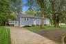Exterior featuring light blue horizontal siding, white trim, a detached garage, a raised deck with stairs, and a concrete driveway