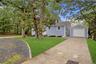 Detached garage, a concrete driveway, a stone-lined gravel path, and mature landscaping