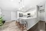 Kitchen featuring white shaker-style cabinetry, white countertops, stainless steel appliances, pendant lighting, and wood-finish flooring