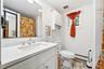 Bathroom featuring a white vanity with a white countertop and integrated sink, a large wall-mounted mirror, white wall-mounted upper cabinetry, and ti