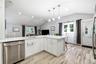 Kitchen featuring white shaker-style cabinetry, white countertops, stainless steel undermount sink, pendant lighting, and wood-finish flooring under a