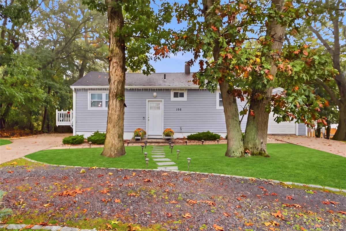 A paved stone pathway, and mature trees situated on a landscaped lot