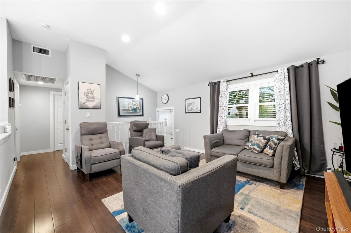 Vaulted ceiling, wood-finish flooring, recessed lighting, and white wooden stair railing