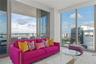 Floor-to-ceiling glass windows, sliding glass doors, and a covered balcony