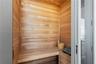 Custom sauna featuring natural wood wall paneling, tiered wood-finish bench seating, and an integrated heating element