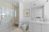 Glass-enclosed walk-in shower with stone wall surround, built-in shower bench, solid-surface vanity countertop with integrated sink, and full-width wa