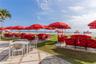 Outdoor terrace featuring stone paver flooring and manicured grass lawn with direct beach access
