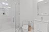 Bathroom featuring a walk-in shower with glass enclosure and tiled walls, built-in shower niche, floating-style vanity with rectangular sink, and wall