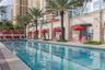 Lap pool featuring stone decking, tile finish, glass railings, and mature palm trees