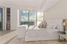 Floor-to-ceiling windows, textured accent wall, integrated recessed lighting, light wood-finish flooring, and a contemporary crystal chandelier