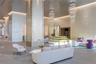 Grand lobby featuring a double-height ceiling, tiered crystal chandelier lighting, textured wall finishes, large-scale structural support pillars, and