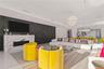 Contemporary living area featuring a stone fireplace surround, dark wood-paneled accent wall, large-format tile flooring, recessed ceiling lighting, a