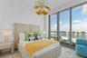 Floor-to-ceiling windows featuring panoramic water and city scenery, combined with a sculptural multi-tiered pendant light fixture