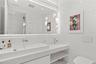 Floating vanity with an integrated basin, expansive wall-to-wall mirror, tiered glass pendant lighting, and recessed ceiling illumination