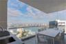 Covered outdoor balcony featuring a built-in outdoor kitchen with sink, glass panel railing, and tile flooring