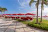 Stone paver terrace featuring manicured lawn, established palm trees, and direct oceanfront access