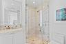 Bathroom featuring a vanity with integrated sink and stone countertop, frameless glass-enclosed shower with stone-surround, wall-to-wall mirror, and r