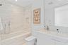 Full-height slab-stone wall surround, integrated recessed shower niche, modern white vanity with matching stone countertop, rectangular undermount sin