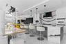 Contemporary kitchen featuring a stone-topped waterfall island, custom cabinetry, a slab backsplash, integrated wall oven, and pendant lighting